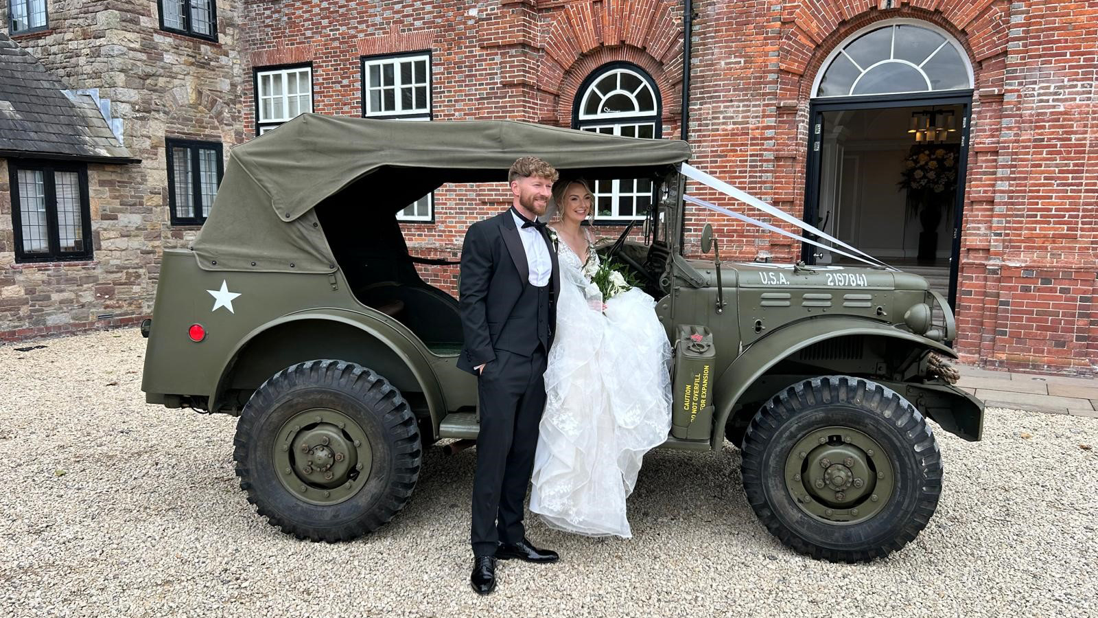 Bride and Groom posing for photos by the Khaki Green Dodge Command Car decorated with Wedding Ribbons