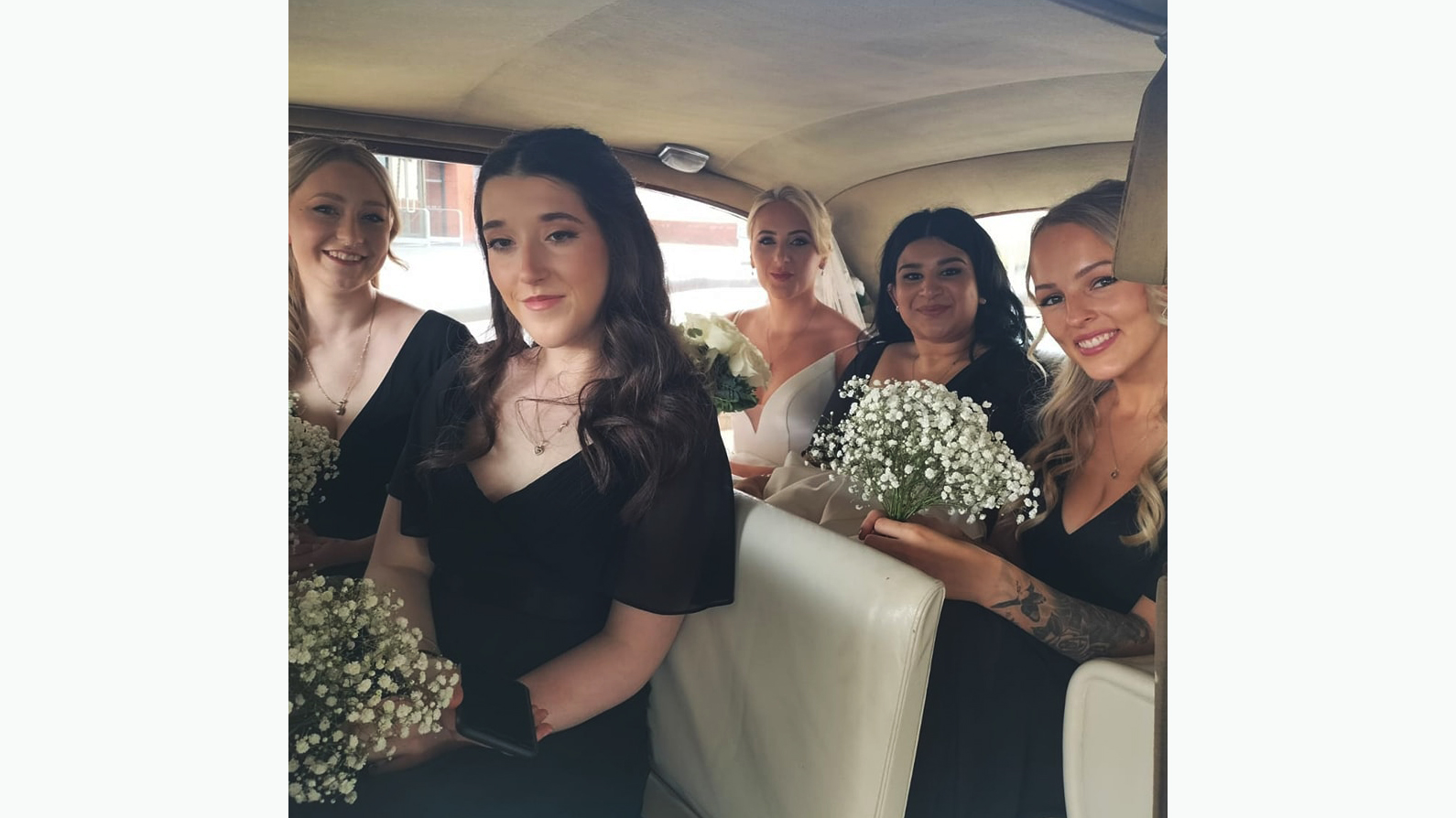 5 passengers seating in the rear of the Austin Princess showing Bride wearing a white dress and 4 Bridesmaids wearing black dresses.