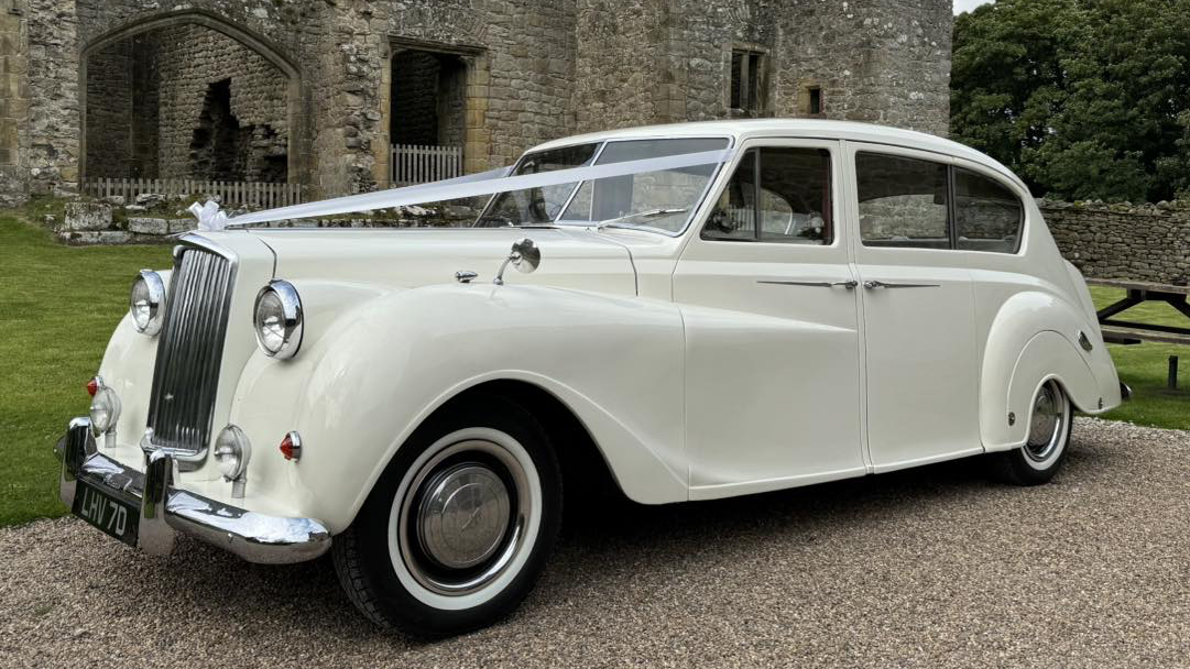 Front left view of classic Austin Princess limousine dressed with Ivory ribbons