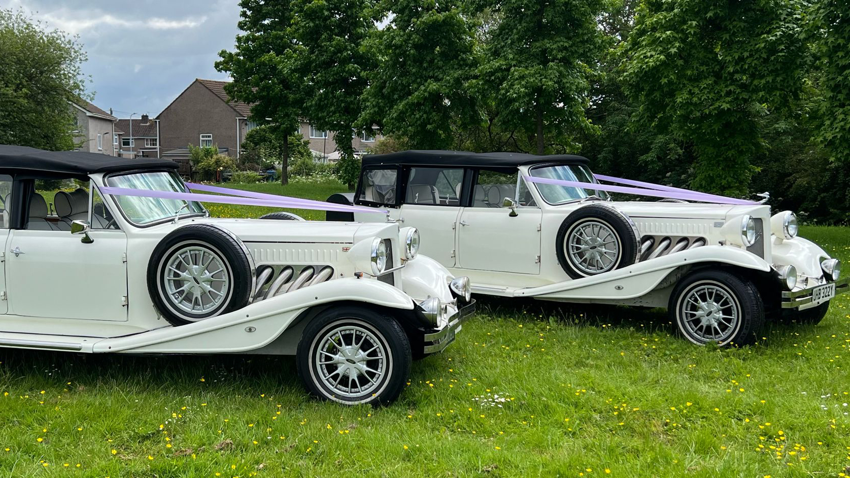 Two identical Beauford wedding cars decorated with matching lillac ribbons