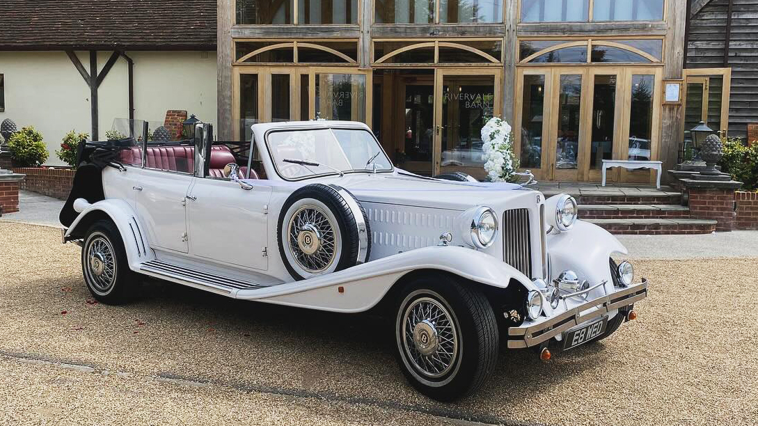 White beauford Convertible with roof down parked in front of a wedding venue.