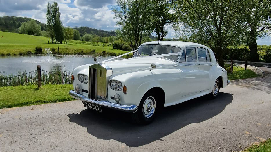 White classic Rolls-Royce Silver Cloud with twin headlights decorated with white ribbons