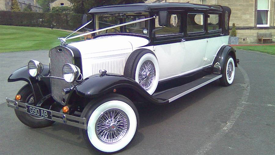 Black and Ivory Bramwith Limousine with wedding ribbons. spokes wheel with white wall tires and spare wheel mounted on the side of the vehicle