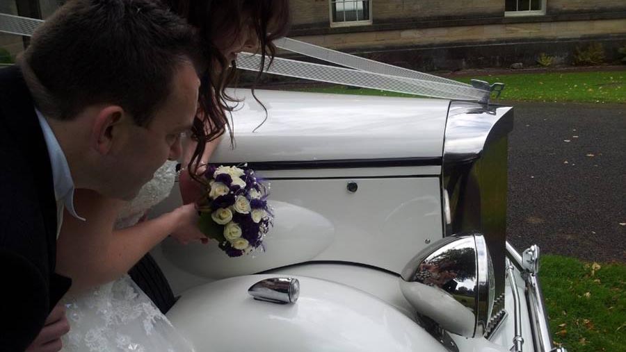 Bride and Groom looking at their reflection on the vintage regent chrome front headlights