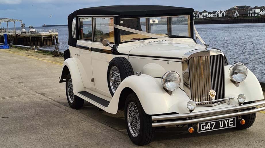 Ivory Regent Convertible with black roof, dressed with ivory ribbons accross its front bonnet with view over Newcastle Quay in the background