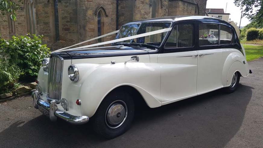 Left side vioew of Classic Austin Princess in Ivory with Black Roof and Bonnet decorated with White Ribbons