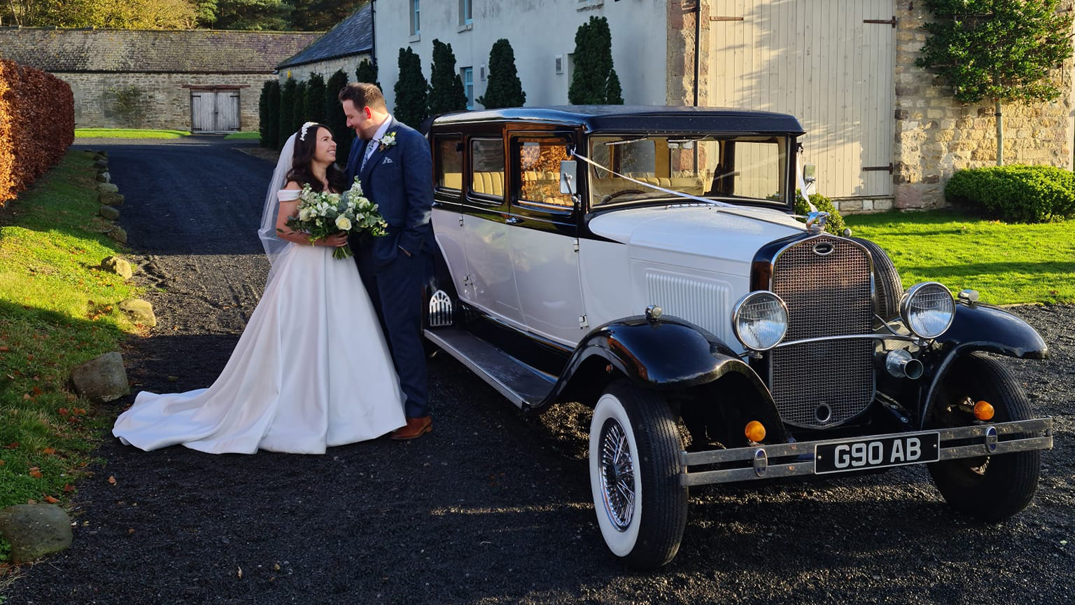 Bride and Groom posing for photos bext to Vintage style Bramwith in Black and Ivory