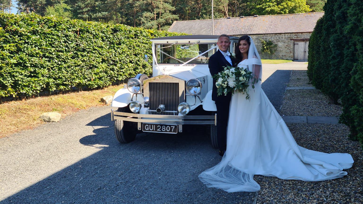 Bride and Groom standing in front of a White Imperial Convertible