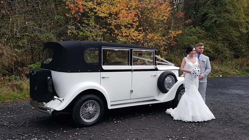 Couple posing for photos in front of Regent Convertible with its black soft top roof closed