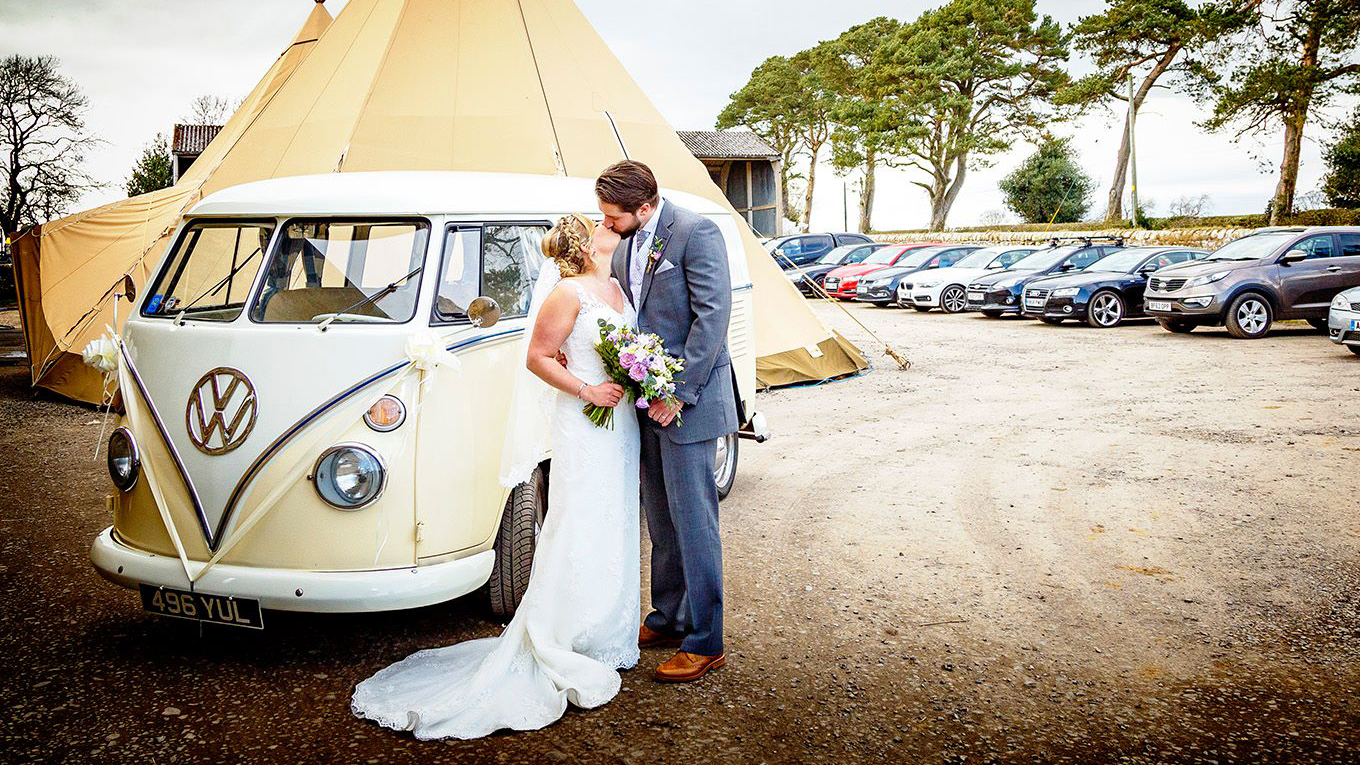 Bride and Groom kissing in front of a Classic VW Campervan.