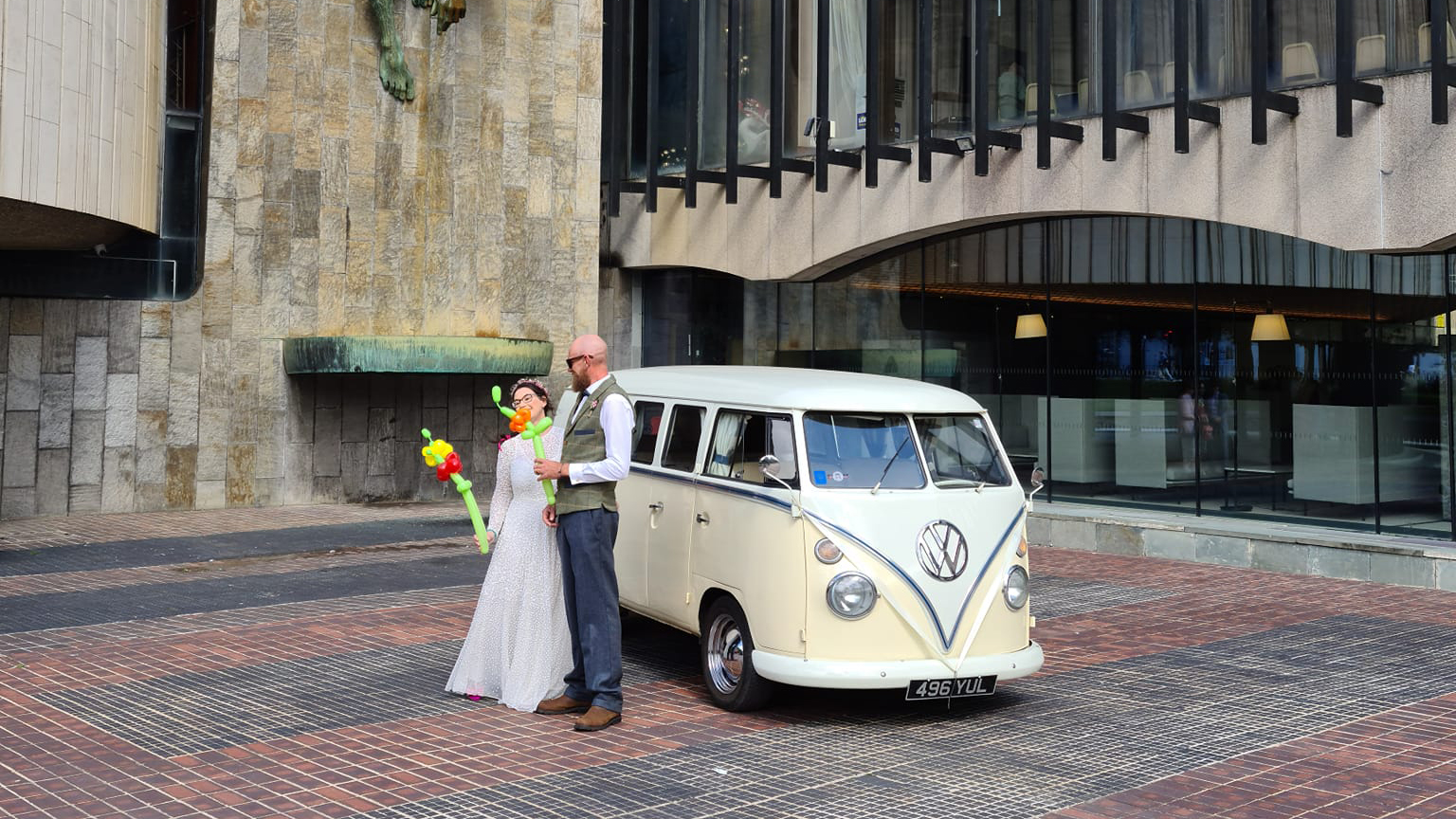 Bride and Groom standing on the side of a Classic VW Campervan in front of Newcastle Registry Office