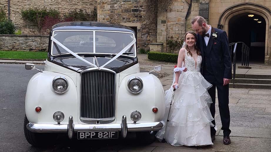 Bride and Groom holding each opther standing next to the Classic Austin Princess