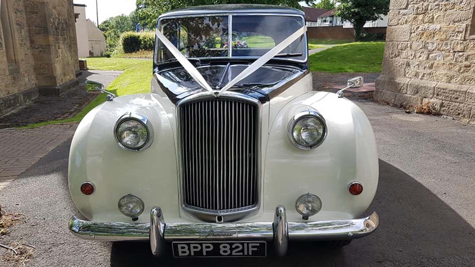 Full front view of ivory Austin Princess with Black Bonnet and white ribbons. Large chrome grill and chrome front bumper.