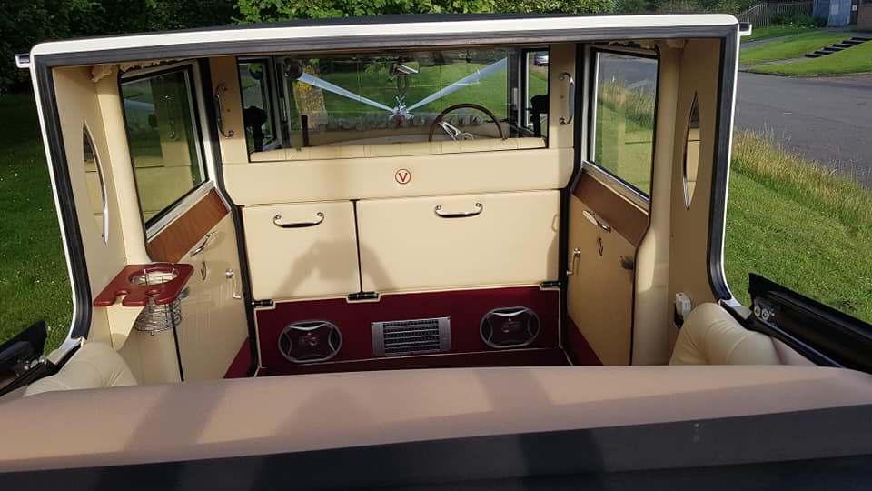 White Imperial with convertible roof down showing the rear compartment seating area with cream leather seats and Burgundy carpet