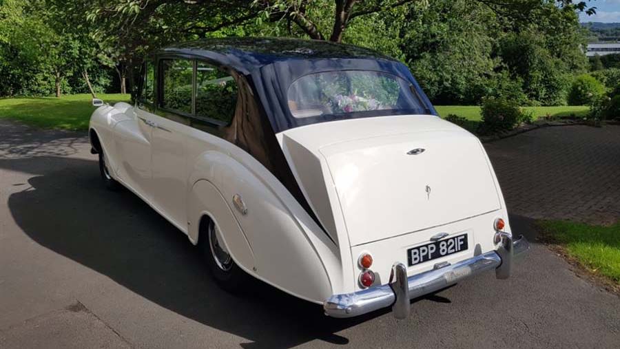 Left rear view of Ivory Austin Princess Limousine with Black Roof and chrome rear bumper