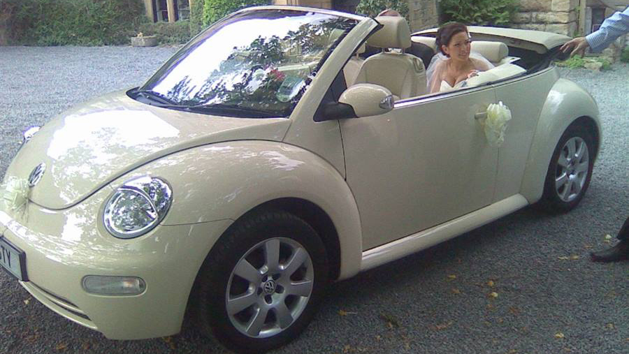 Bride seating in the rear seat of a Convertible Modern VW Beetle in Cream