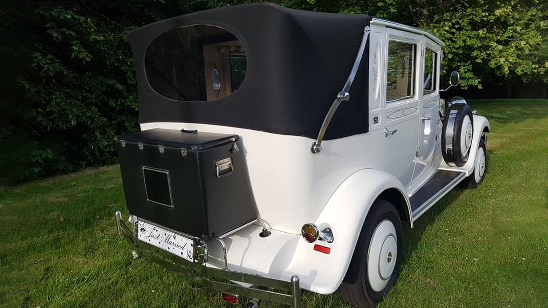 Rear view of White Imperial Convertible wedding car with black soft top roof close and black picnic trunk at the rear