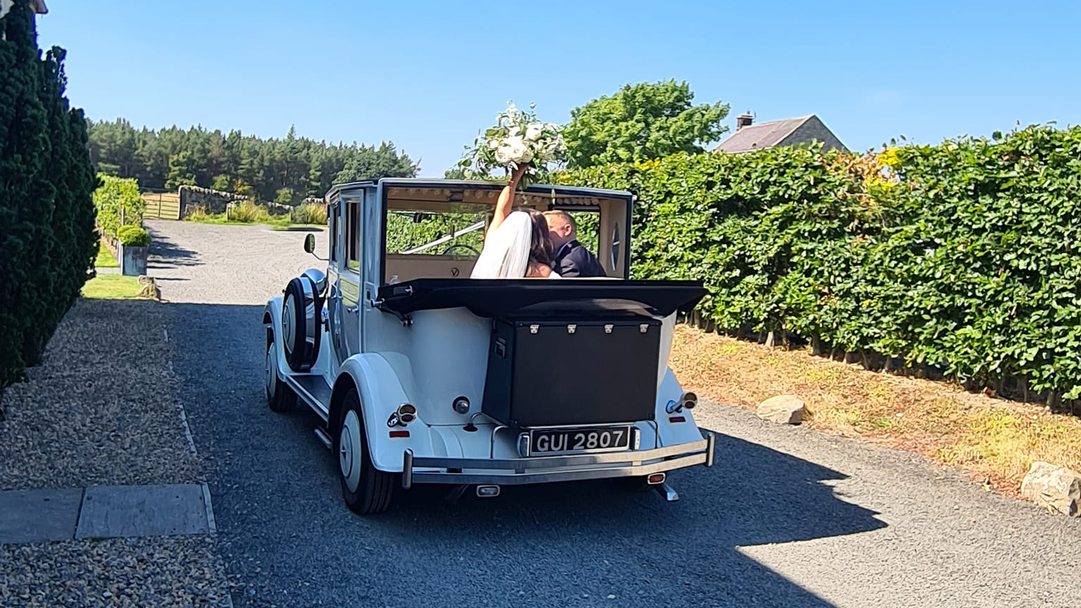 White Imperial with Convertible roof open showing Bride and Groom inside the vehicle kissing