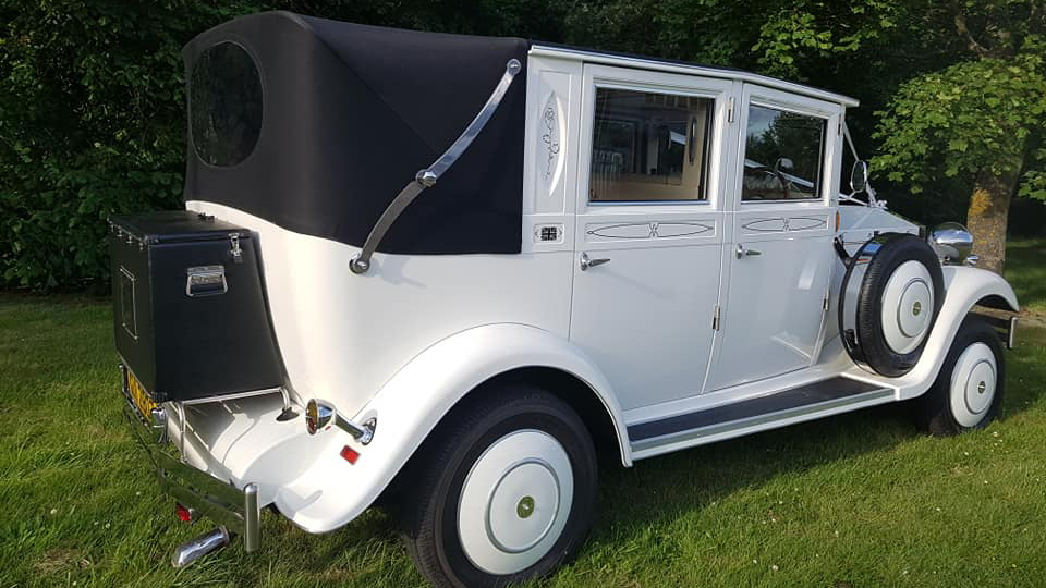 Right rear view of vintage style imperial with black soft top roof closed and spare wheel mounted on the side of the vehicle