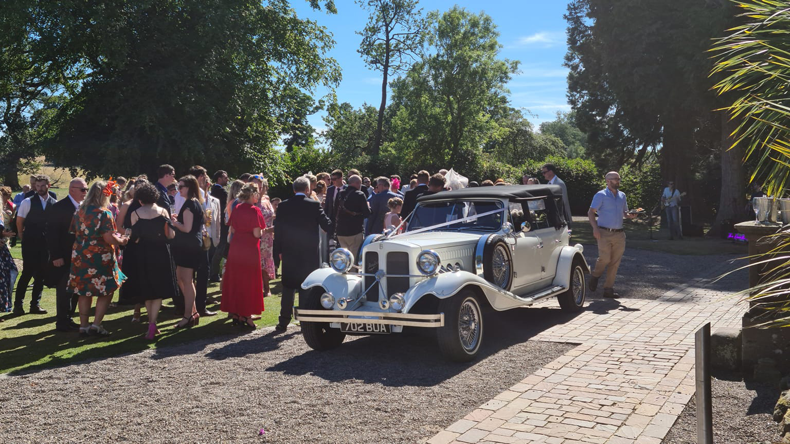 Beauford Convertible dressed with wedding ribbons accross its bonnet and wedding party in the back ground