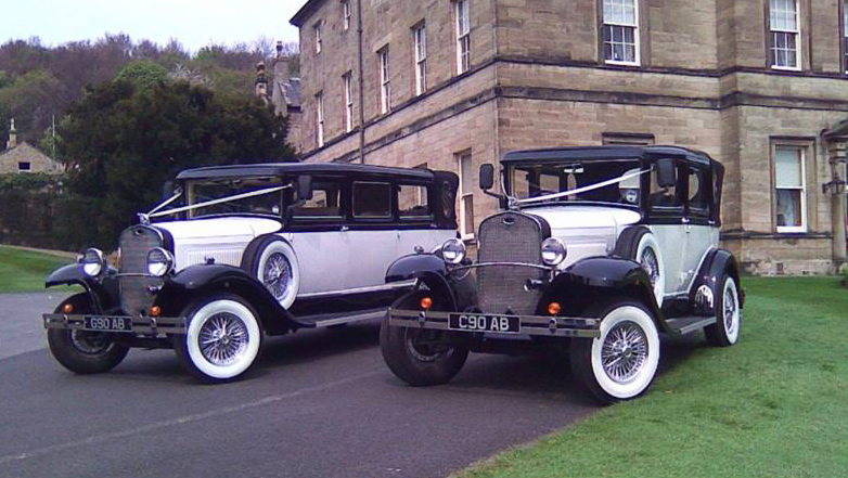 Badsworth and Brammith wedding cars with matching colour of Ivory and Black and White ribbons parked next to each others in front of a wedding venue.