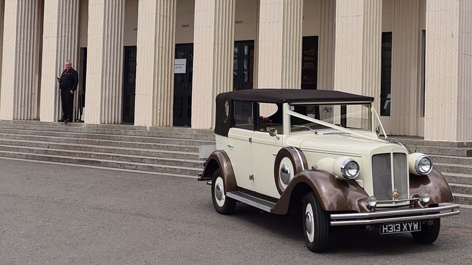 Vintage Regent Convertible with soft top roof closed, dressed with white ribbons in front of Wylam Brewery wedding venue in Newcastle