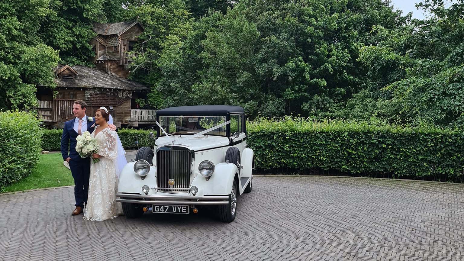 Bride and Groom standing next to a Regent Convertible wedding car