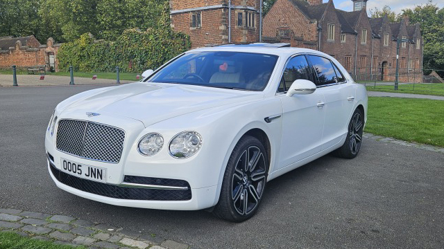 Front Left side View of White Bentley Flying Spur with large black and Chrome Alloy wheels