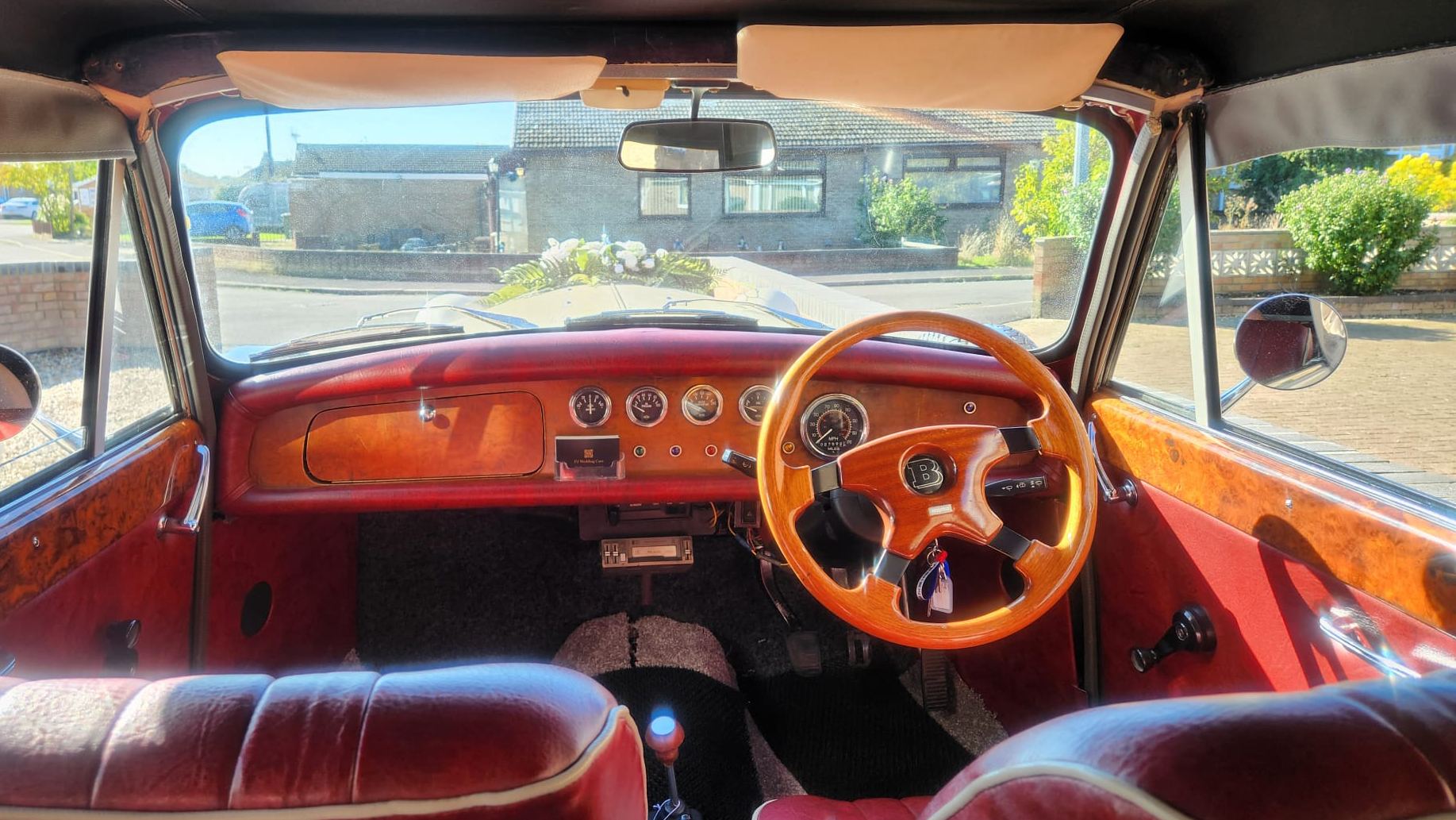 front driver seat photo taken from the rear seat shwoing wooden steering wheel and dashboard