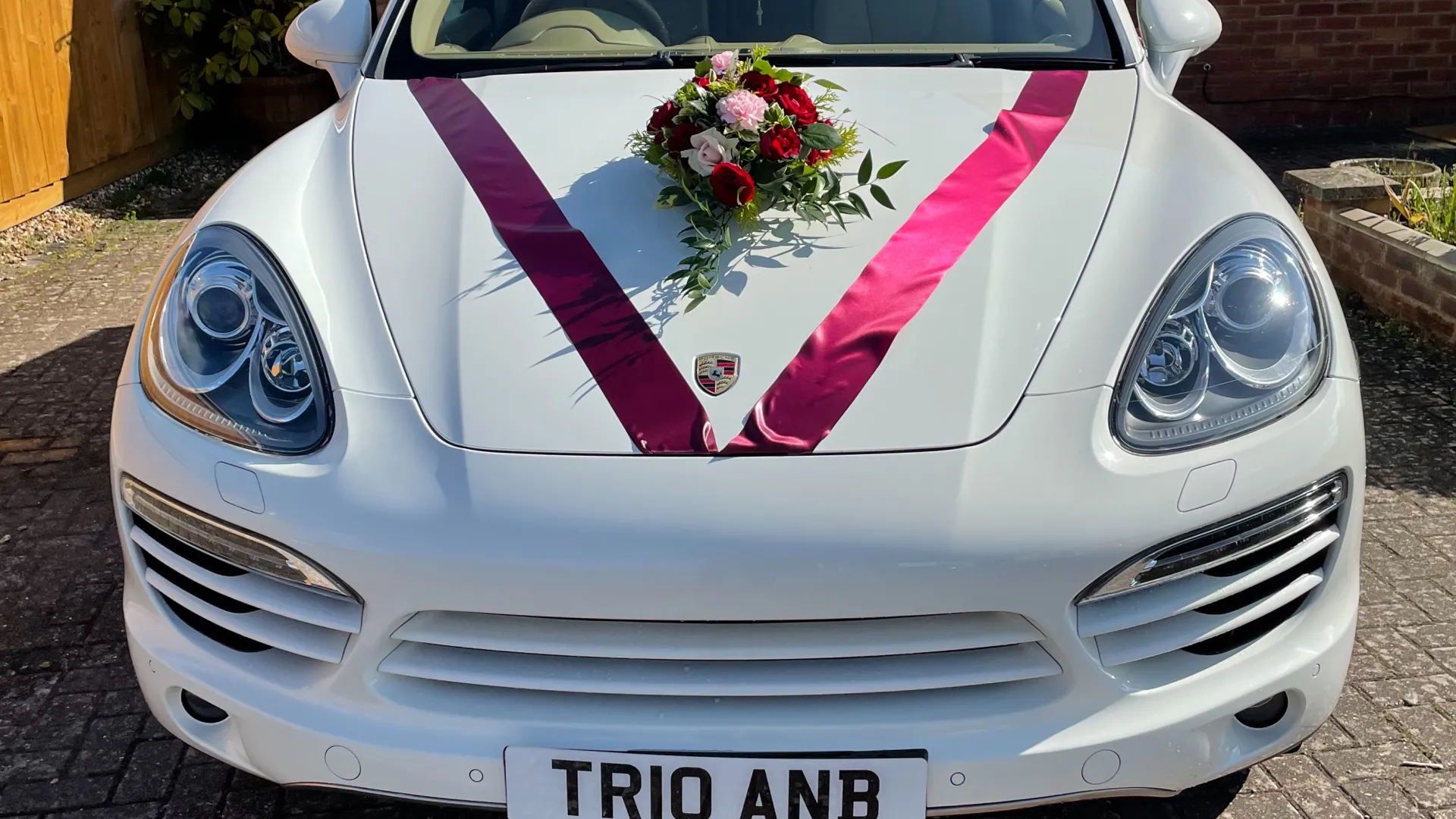 Front view of Whtie Porsche Cayenne with Burgundy ribbons and flowers on front bonnet.