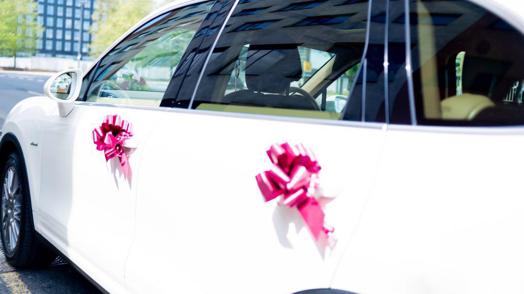 Fushia Pink bows attached to the door handles of a white Porsche Cayenne