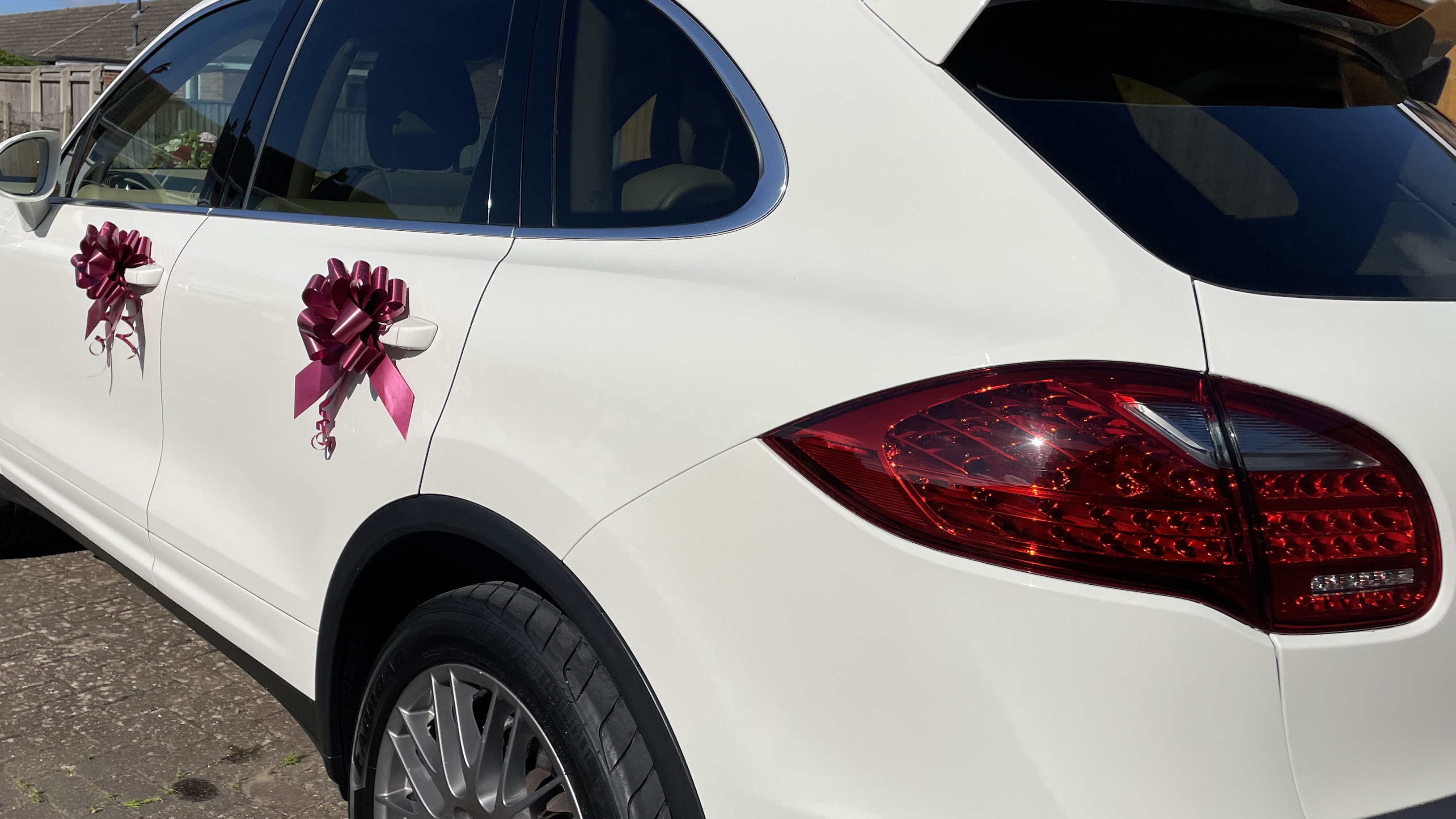 Burgundy bows attached to the door handle of a modern white car