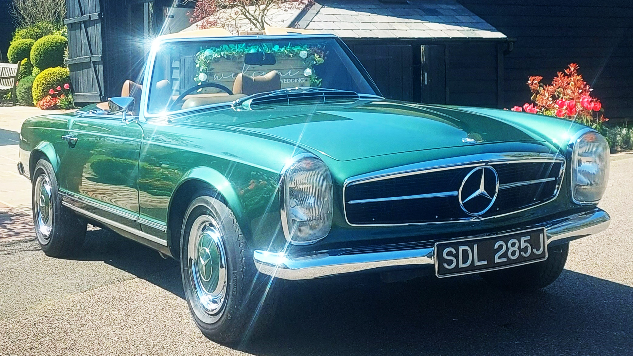 Metallic Aqua Green Mercedes 280sl Convertible parked in front of a wedding venue