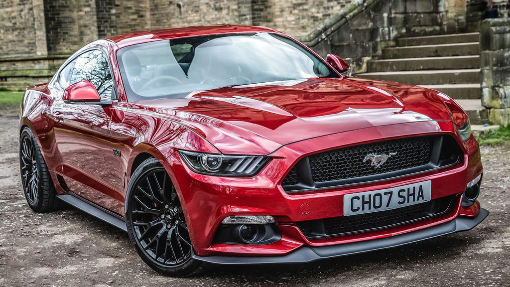 Front right view of a Modern ford Mustang in Cherry Red with black alloy wheels