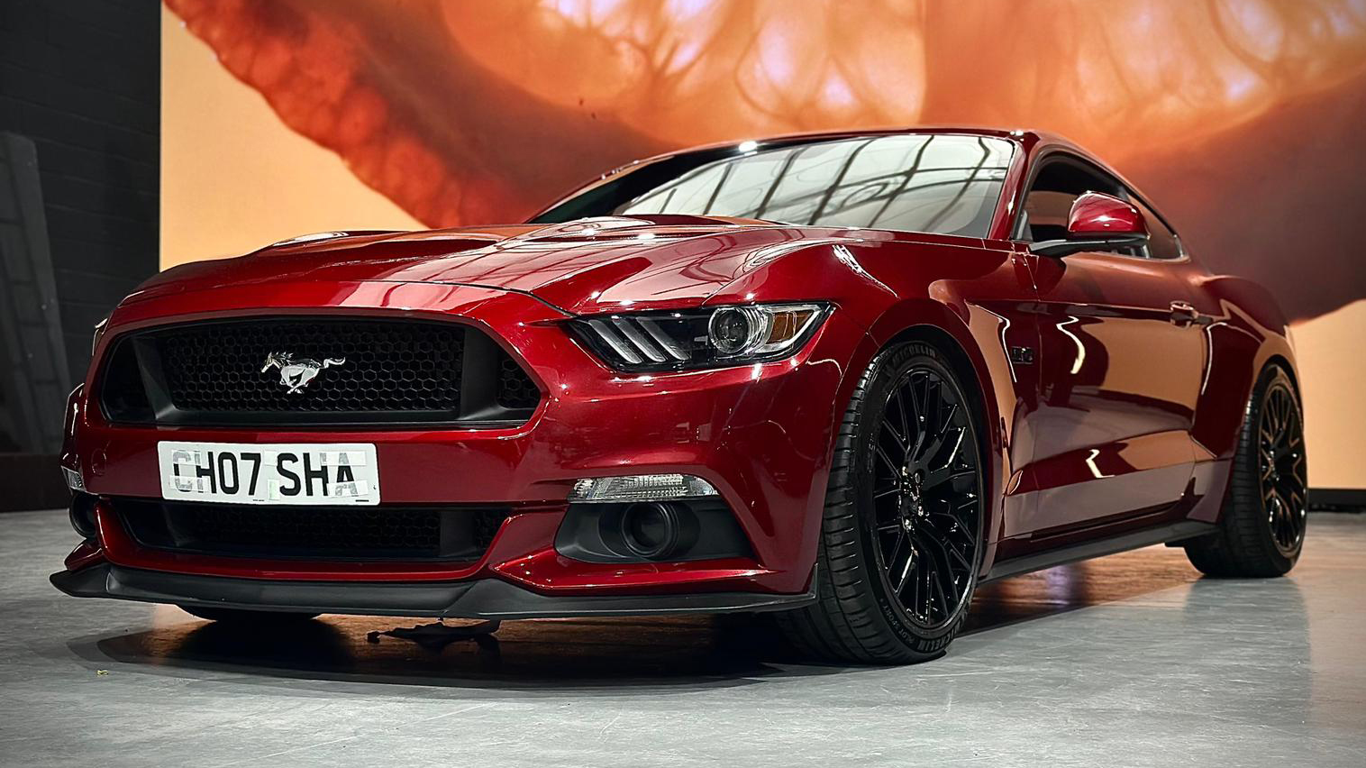 Front left side view of modern GT Mustang with black front grill and chrome Mustang Poney Logo