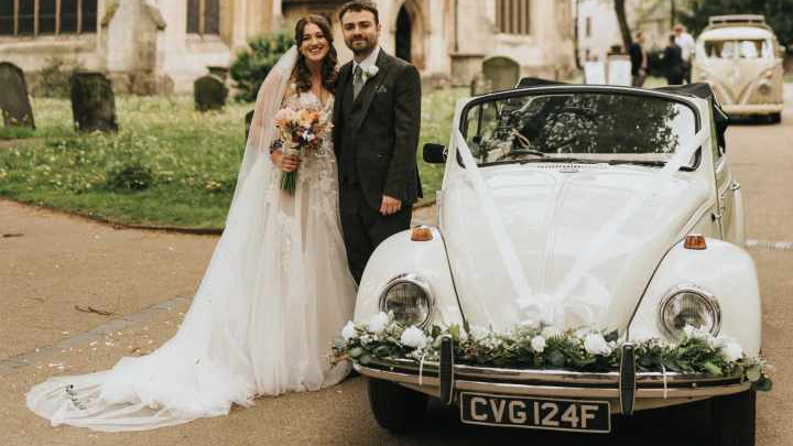 Bride and groom standing by a classic VW Beetle