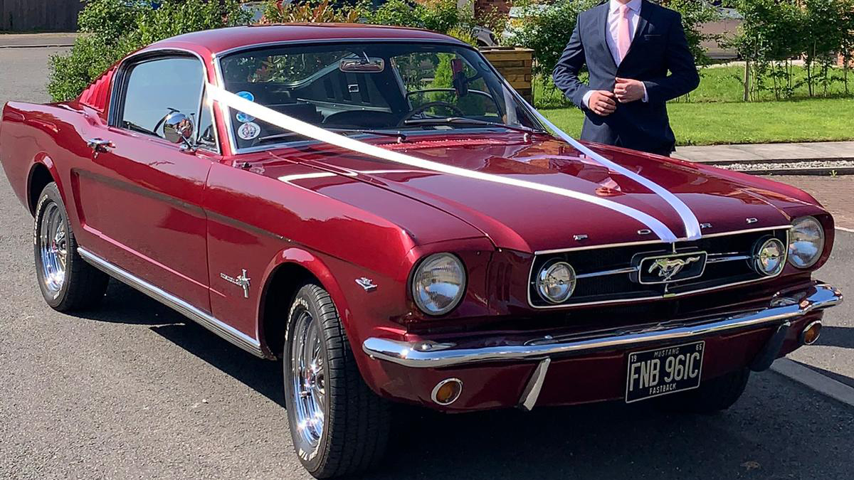 Cherry-red Classic Ford Mustang decorated with white ribbons