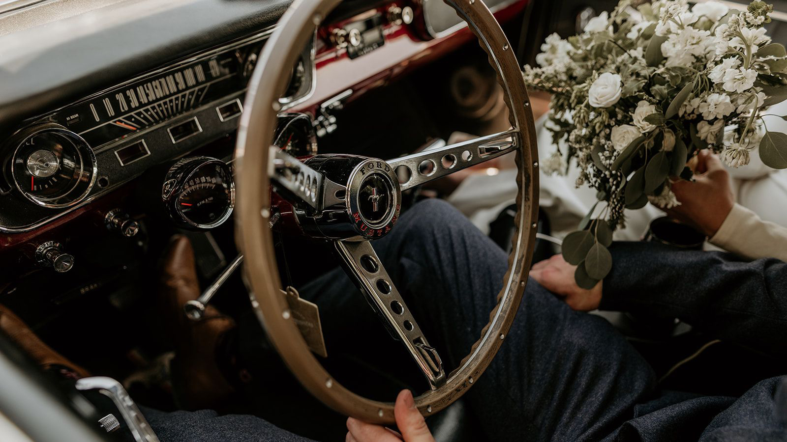 Front Dashboard with wooden steering wheel and bridal bouquet on the right of the photo