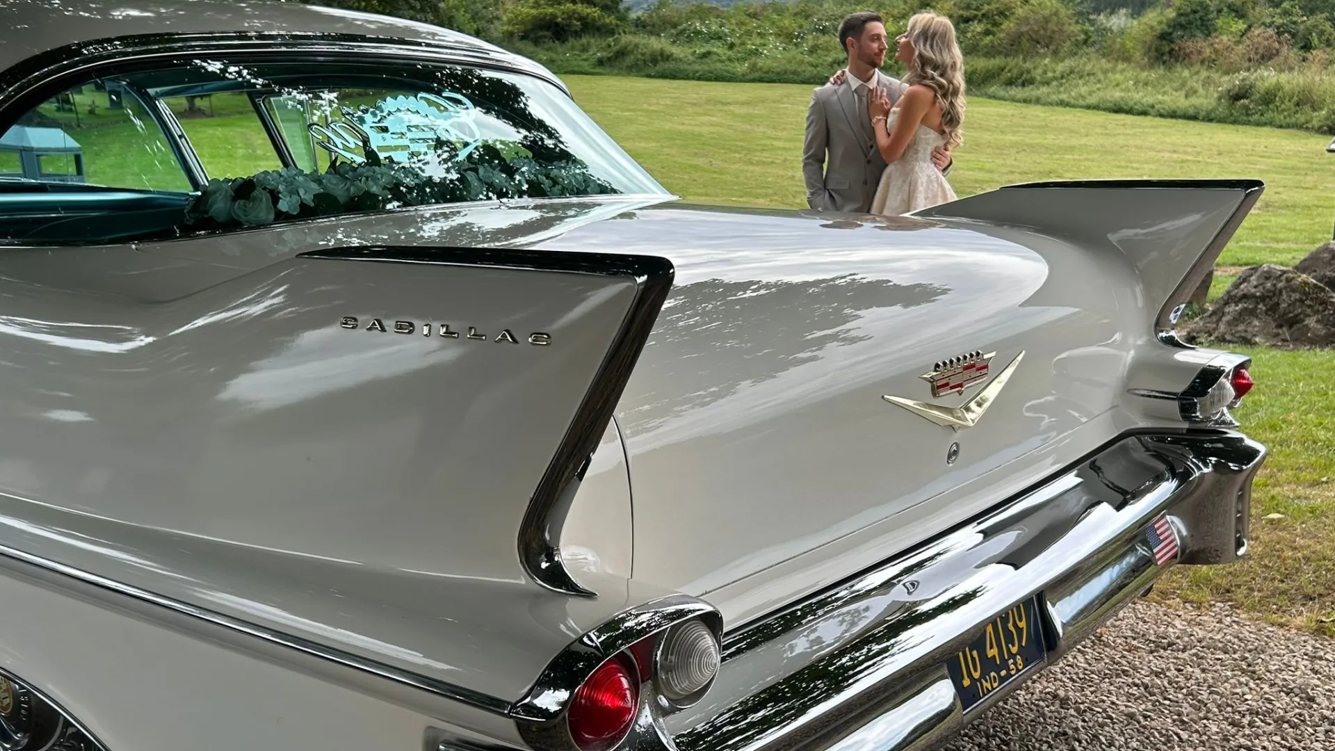 Rear thin tail of a white classic american Cadillac with Bride and Groom in the background