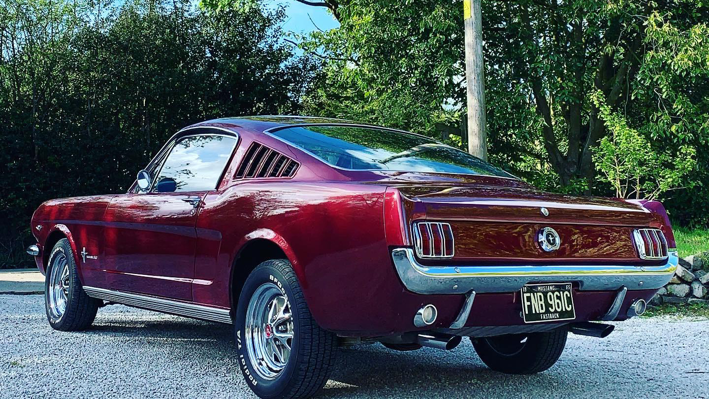 Left rear view of Classic Ford Mustang in Cherry Red with chrome bumper and chrome Alloy wheels