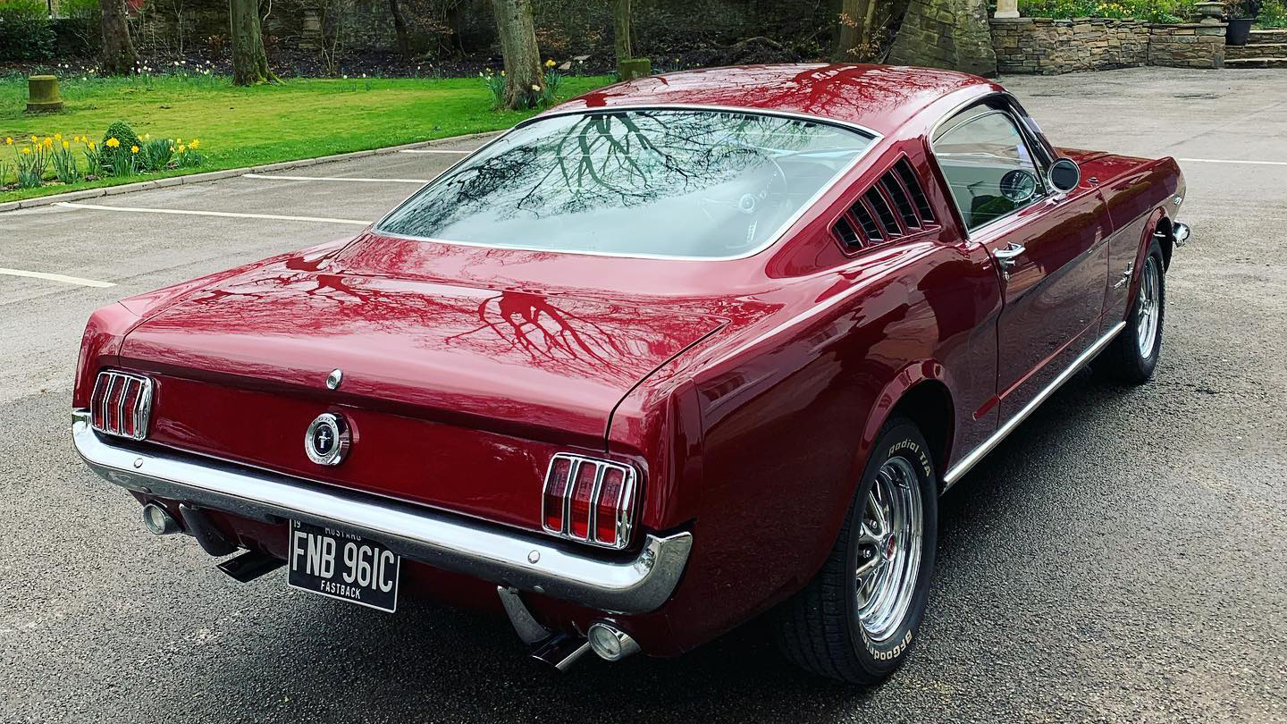 Rear view of Classic Cherry-Red Fastback Ford Mustang with chrome rear bumper