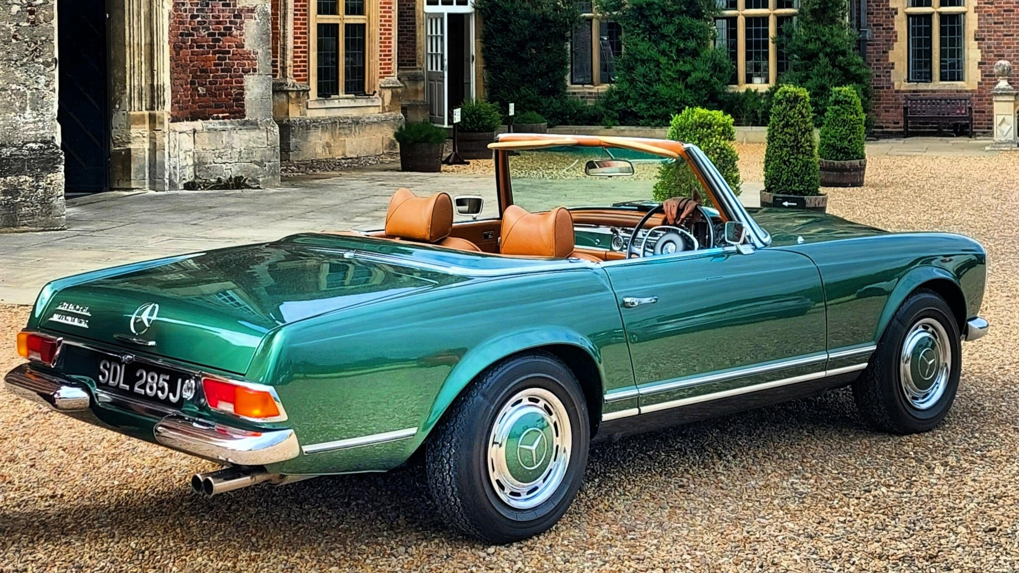 Rear view of classic Mercedes in Metallic Aqua Green with convertible roof down showing a light Tan Leather interior