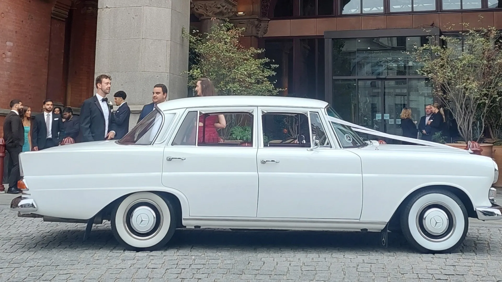 Right side view of white Mercedes parked in front of a wedding church.