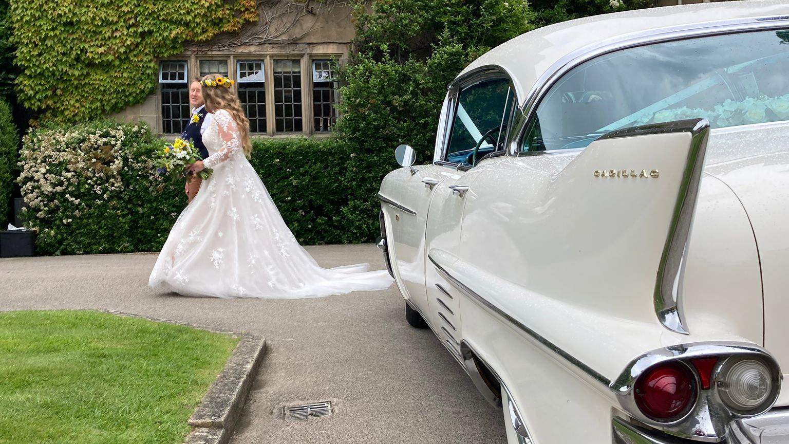 Left side view of a white classic American wedding car with Bride and Grom in the background