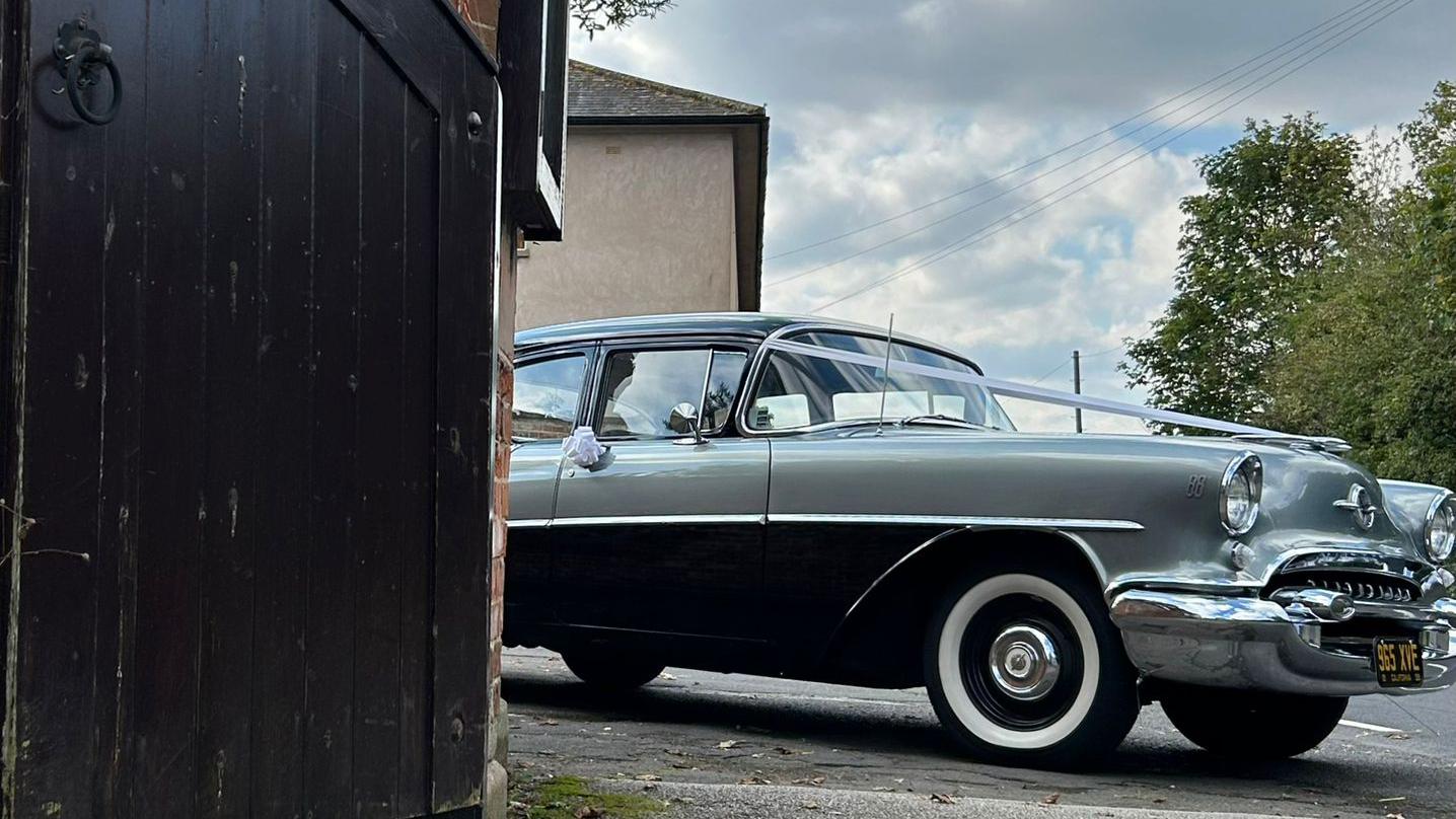 Right side view of classic American Oldsmobile in Black and Silver with white wall tires.