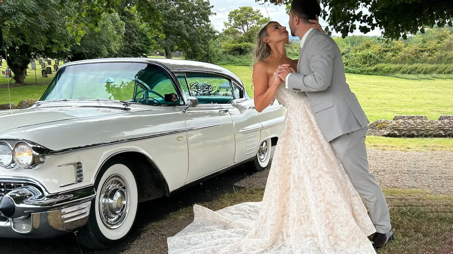 Bride and Groom holding each others in front of a classic White Amrican wedding car