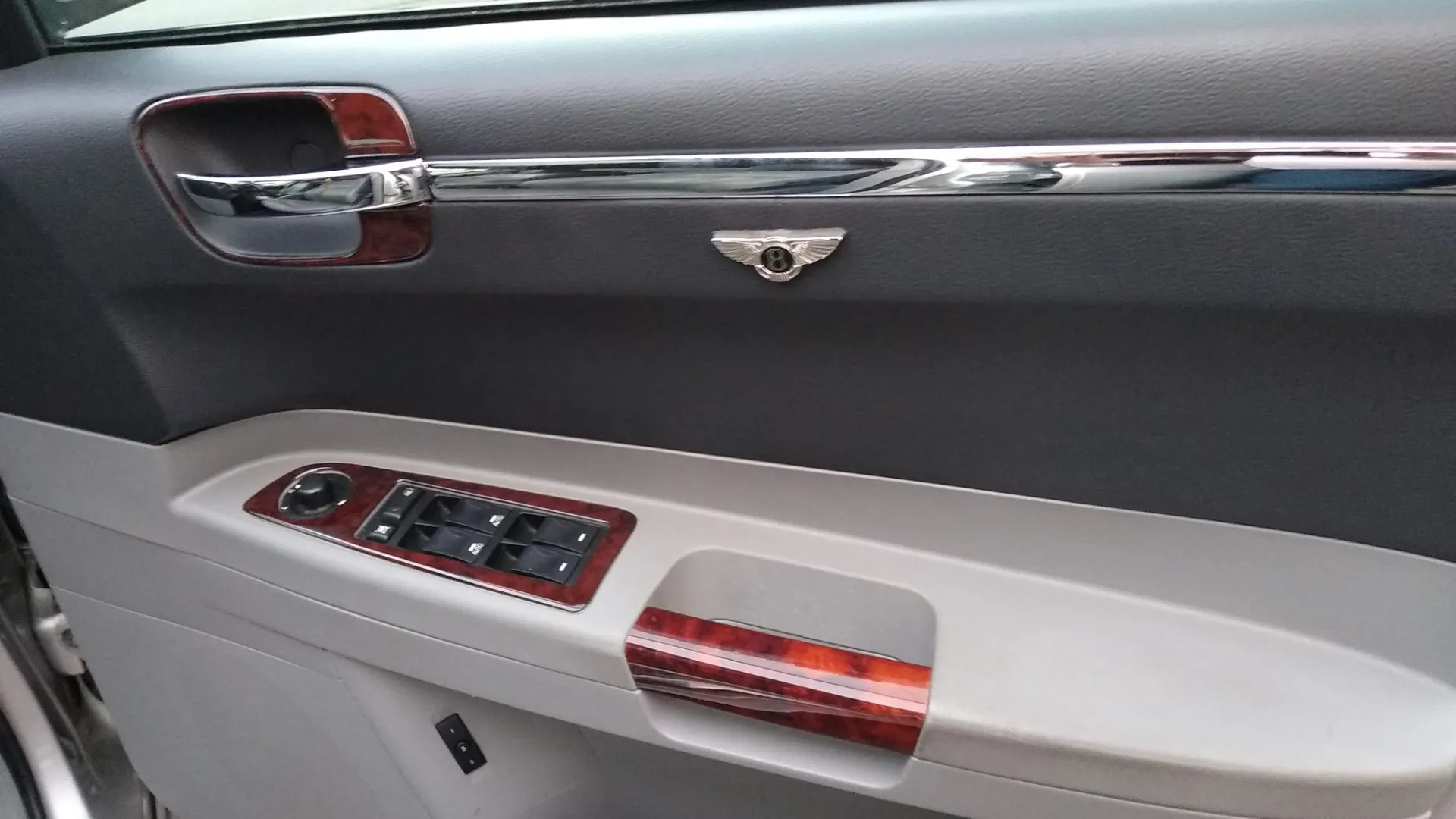 Silver and Grey door panel inside Chrysler 300c saloon car with wooden features