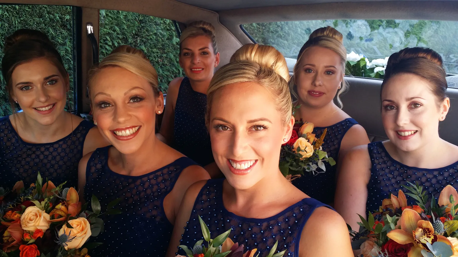 6 Bridesmaids seating in the rear cabin of Daimler Limousine wearing matching Blue Dresses