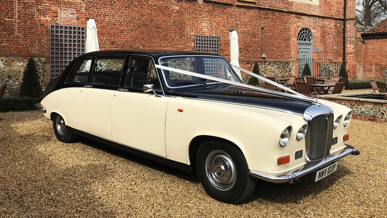 Classic Daimler in Black and Ivory with white ribbons in front of wedding venue