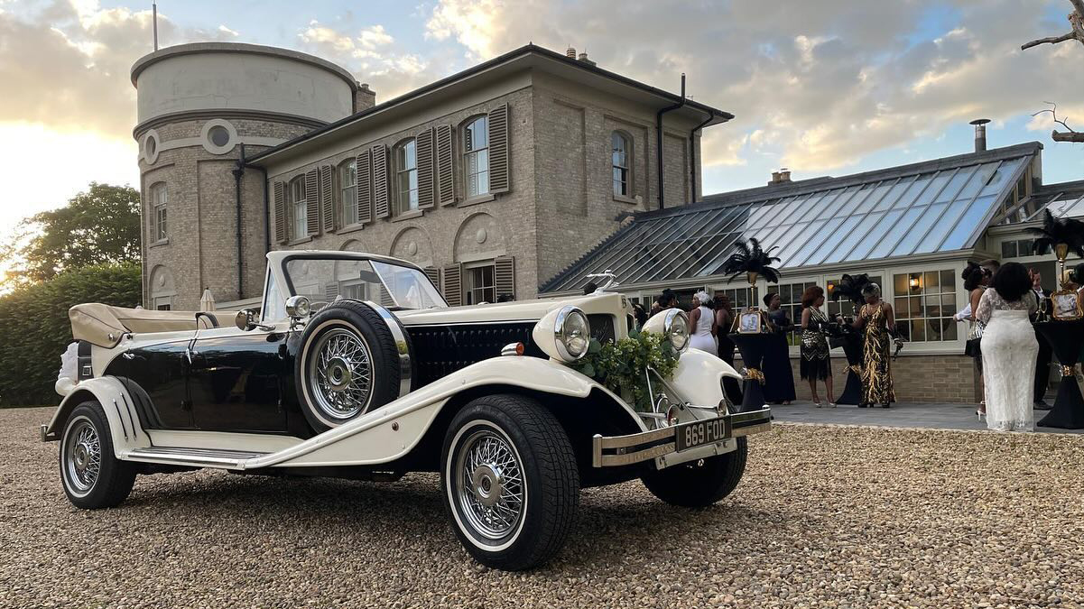 Convertible Beauford in Black & White in front of wedding venue with guersts in background wearing 30s themed clothes